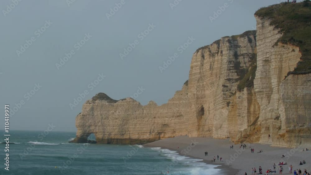 Tourist found on the shore of the beach in Etretat and the big cliff on the background Tourist found on the shore of the beach in Etretat and the big cliff on the background