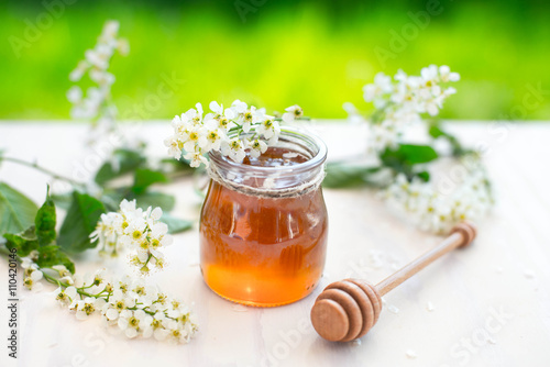 Honey and acacia flowers with a wooden dipper on garden background.