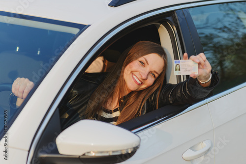 Attractive young woman proudly showing her drivers license