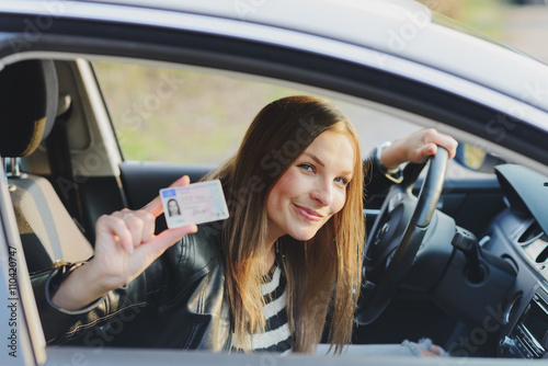 Attractive young woman proudly showing her drivers license photo