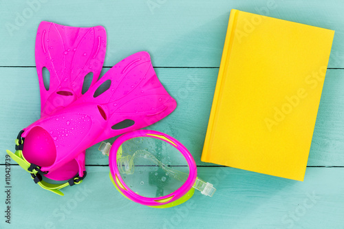 Bright flippers, goggles and book on a green table photo