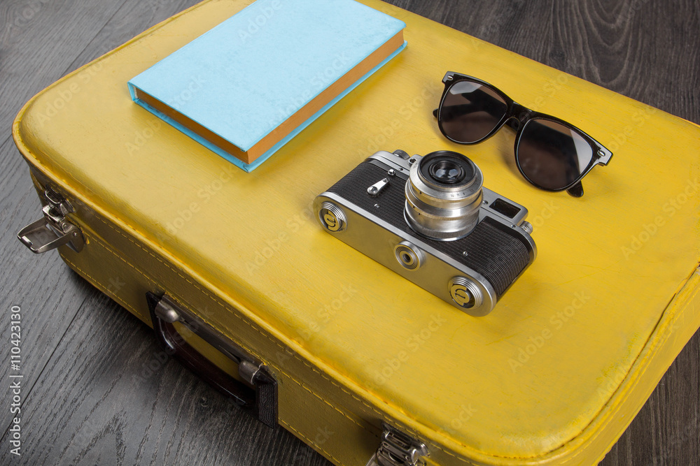 Sunglasses, vintage camera and book on yellow valise on dark  background.Travel concept. Stock Photo | Adobe Stock