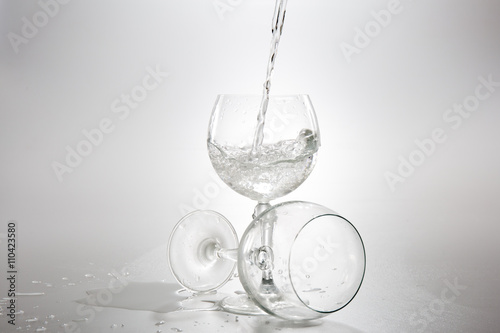 Water pouring from bottle into the glass, isolated on white