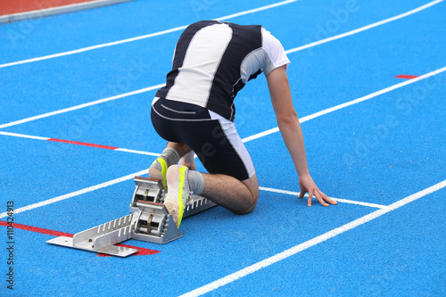 muscular young athlete in the starting blocks of a athletic trac photo