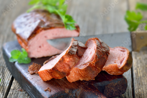 Ofenfrischer bayerischer Leberkäse rustikal auf einem Holzbrett serviert - Bavarian meat loaf on a wooden cutting board 