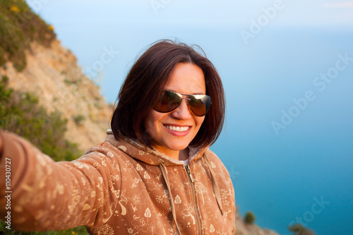 girl shooting selfie on mountain top on background of sea