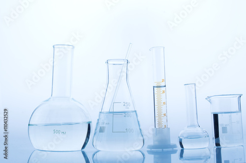 Different laboratory glassware with water and empty with reflection on white background