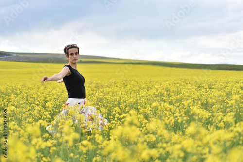Hipster girl walking through a canola field. Freedom concept