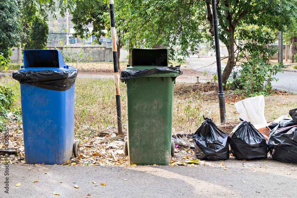 Old large wheel bins and pile of full garbage bags Old large wheel bins and pile of full garbage bags