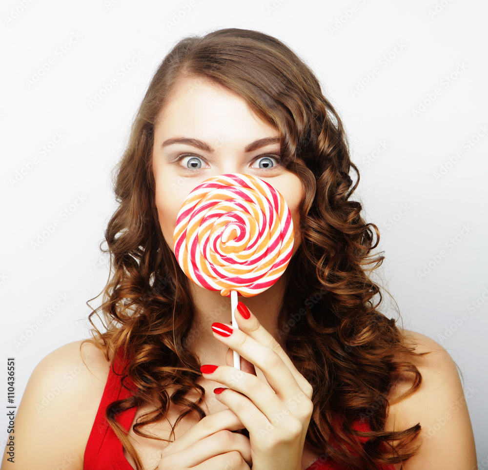 portrait of a smiling cute girl covering her lips with lollipop