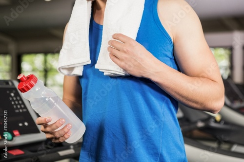 Man on treadmill holding water bottle at gym