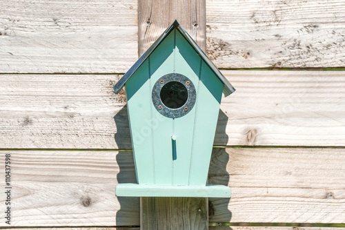 Fototapeta Blue birdhouse on a wooden fence