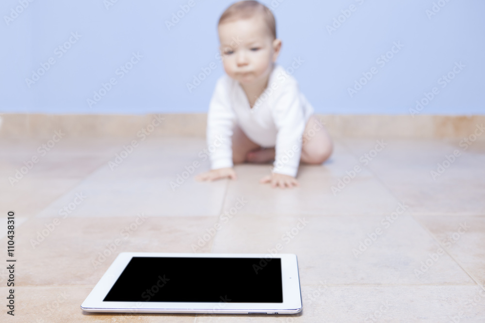 Baby boy crawling to a tablet Baby boy crawling to a tablet