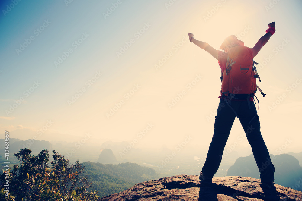 silhouette of young successful woman hiker on mountain peak