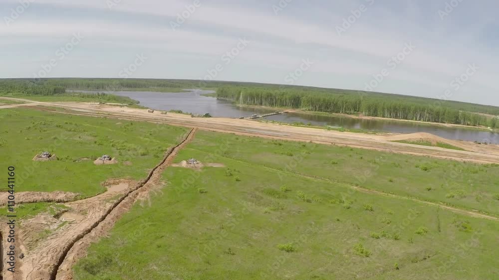 Aerial shot of convoy of military trucks crossing the river bridge during land power maneuvers Aerial shot of convoy of military trucks crossing the river bridge during land power maneuvers