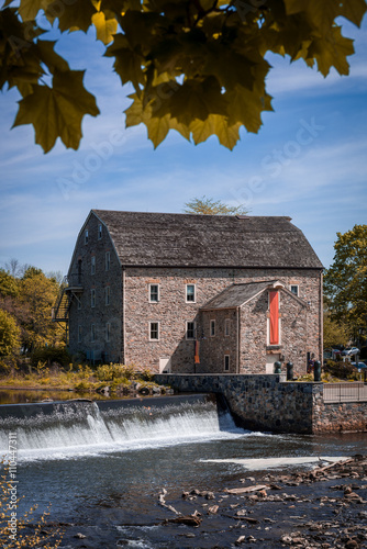 Fototapeta Antique gristmill along side river with dam