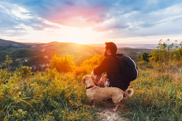 Man with dog enjoying mountain sunset