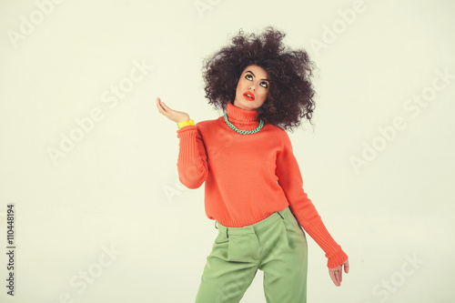 Young woman wearing retro clothes striking a pose in studio. Disco diva