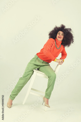 Young woman wearing retro clothes striking a pose in studio. Disco diva