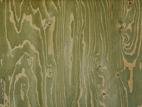 greenish wood panel with streaks created by knots and wavy shaped veins.