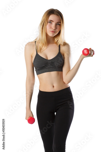 Portrait of attractive cheerful fitness girl in gray top and black leggings with red dumbbells posing over white background isolated 