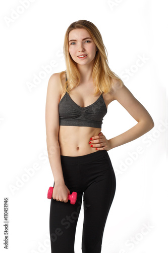 Portrait of attractive cheerful fitness girl in gray top and black leggings with red dumbbells posing over white background isolated