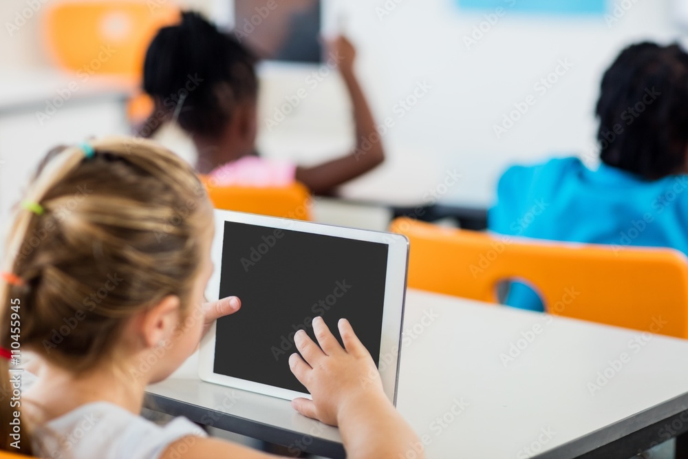 Fototapeta premium Rear view of pupil using tablet pc in classroom