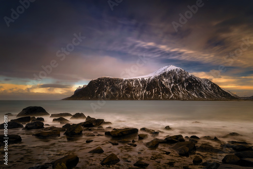 Colorful sunset at Skagsanden rocky coastline with Hustinden mountain, Lofoten 