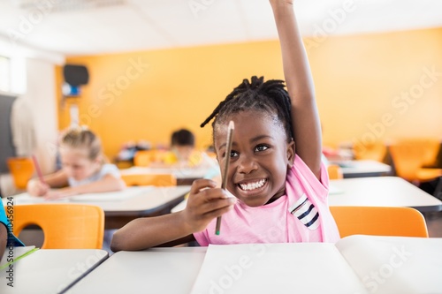 Valokuva A cute pupil raising hand