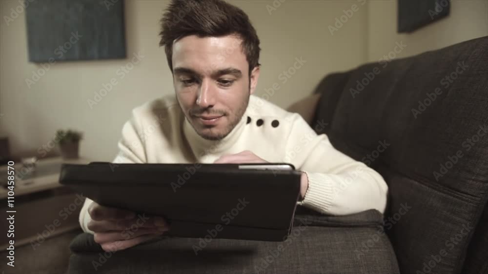 Caucasian man using digital tablet on sofa Caucasian man using digital tablet on sofa