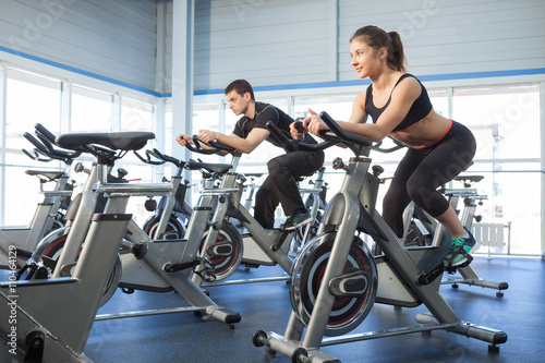 Man and woman exercise bikes at the gym