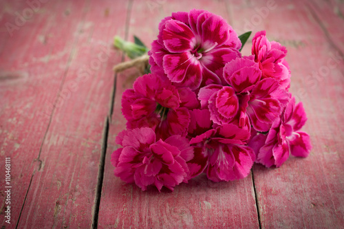 Bouquet of purple carnations on pink wooden background
