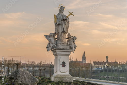 Sonnenuntergang in Regensburg mit Blick auf eine heiligen Statue und Dom in Hintergrund photo