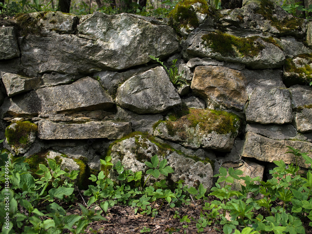 Old stones and moss on a stone wall. Green grass. Old stones and moss on a stone wall. Green grass.