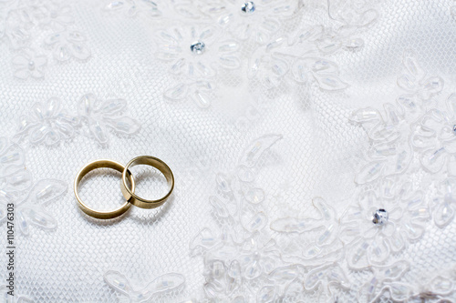 Two wedding rings laying on wedding dress