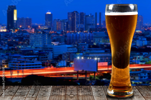 Glass of beer on a wooden City at night background.