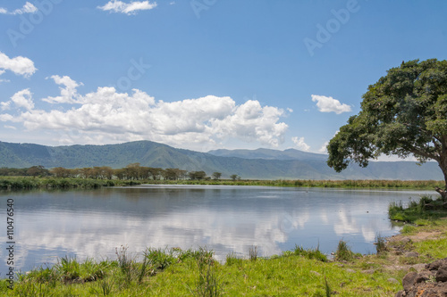 View on huge Ngorongoro caldera (extinct volcano crater) from within with lake before mountain ridge against blue sky background. Great Rift Valley, Tanzania, East Africa. 