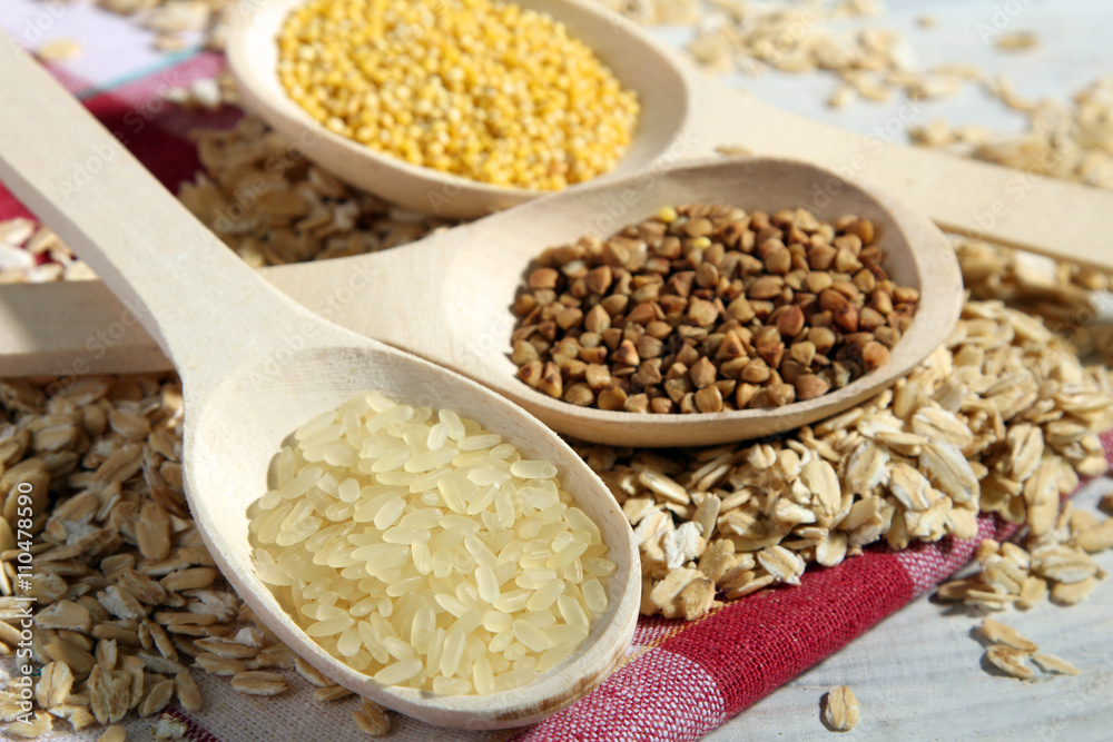 various cereals in wooden spoons on a white wooden table various cereals in wooden spoons on a white wooden table