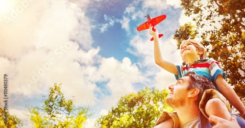 Boy with toy aeroplane sitting on fathers shoulders
