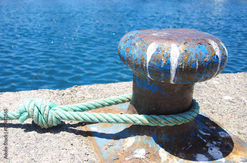 Old mooring bollard with  tied knot at a Harbor photo