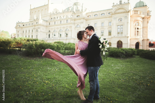 Wedding. Couple. Krakow. The bride in a pink dress and groom posing on background of theater