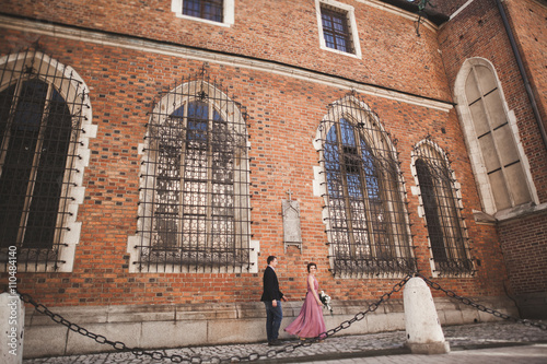 Gorgeous wedding couple, groom and bride with pink dress walking in the old city of Krakow