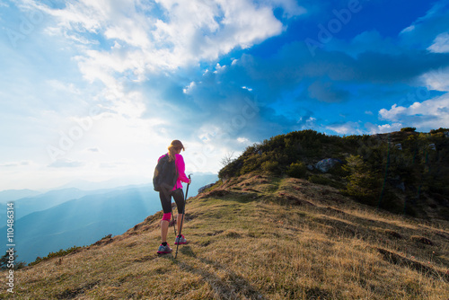 Slender woman practicing nordic walking in the mountains