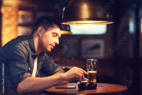 man drinking beer and smoking cigarette at bar