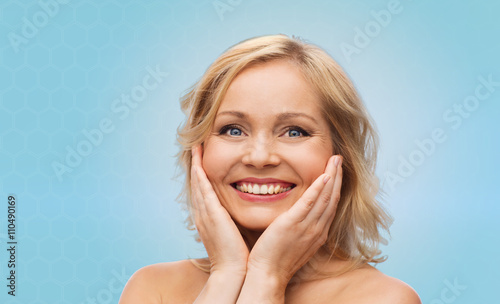 smiling woman with bare shoulders touching face