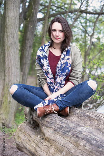 portrait of young woman sitting on a tree