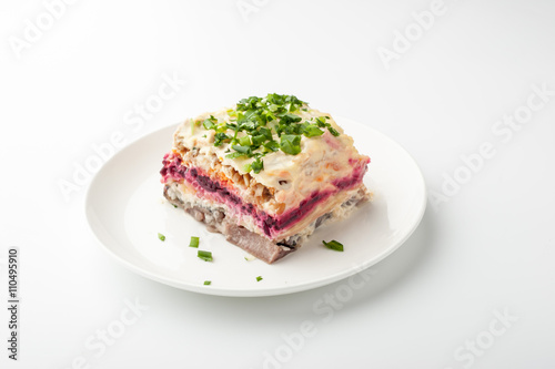 Herring under beetroot and mayonnaise in a white ceramic plate