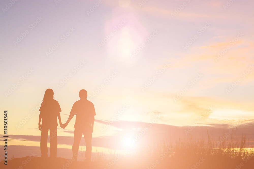 Silhouette of a female and male holding hands at sunset