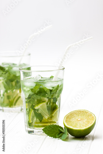Mohito mojito drink with ice mint and lime on wooden white table.