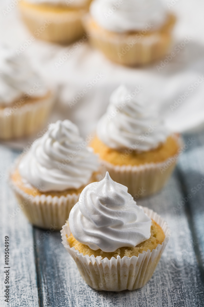 Vanilla cupcakes with white cream on wooden table, whipped cream, selective focus Vanilla cupcakes with white cream on wooden table, whipped cream, selective focus